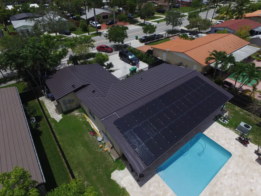 Aerial view of an all-black solar array on a standing-seam metal roof in Miami-Dade