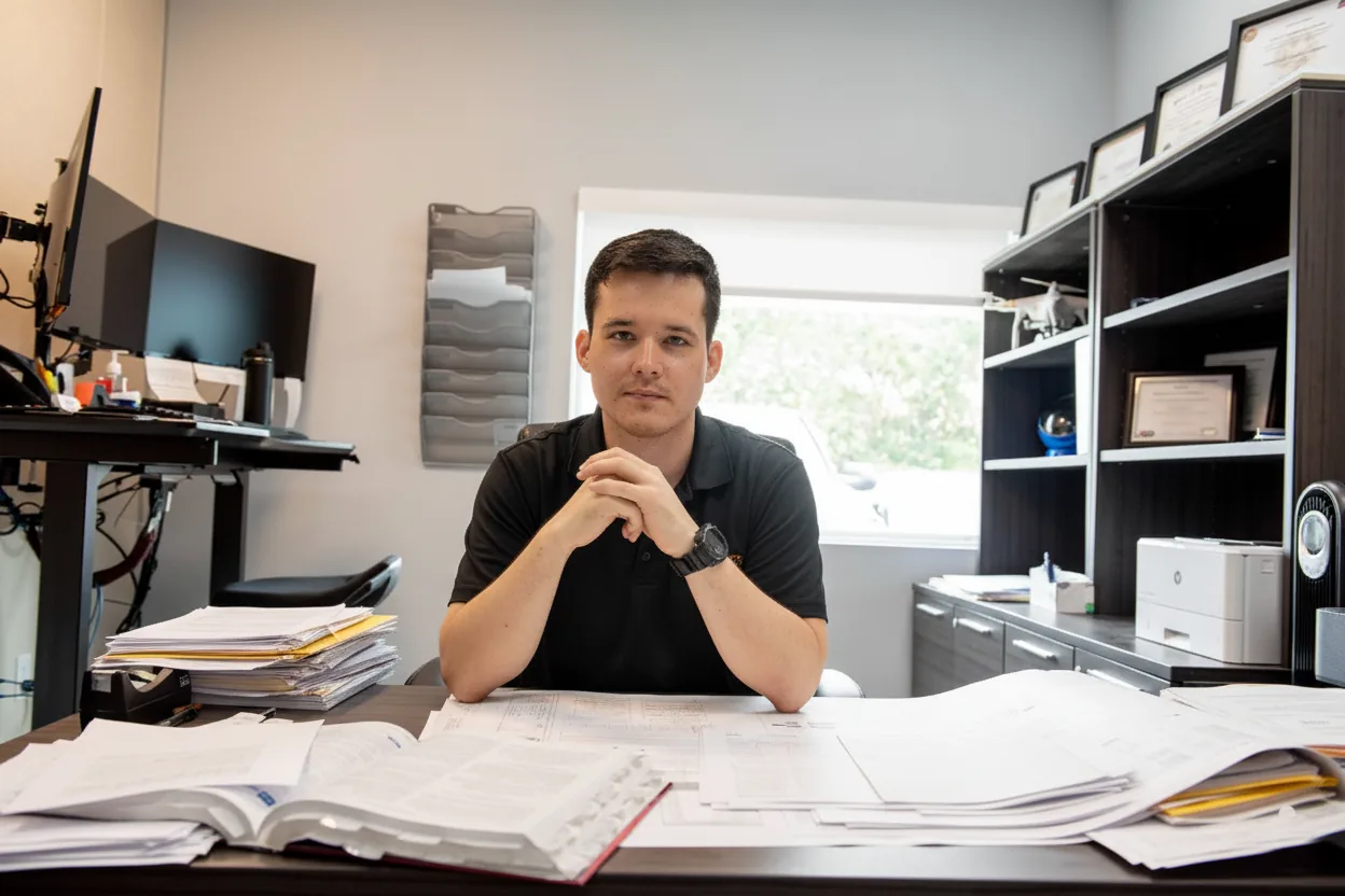 Eduardo Rodriguez at his desk surrounded by plan sets and code books